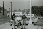 Man with camera and others in parking lot, Farmville, Va., August 1963, #002